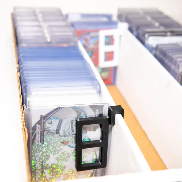 Top-down view of white CardBlock keeping trading cards upright in a storage box row